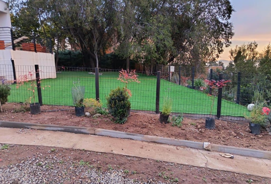Zona de juego cercada con pasto y plantas